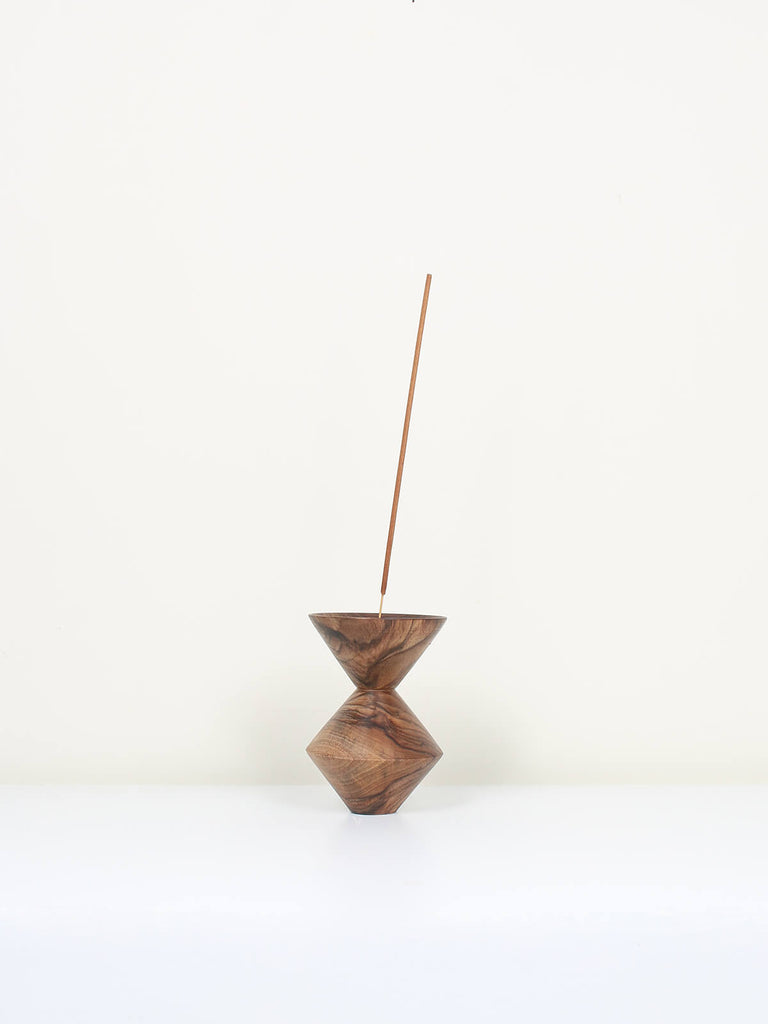 Natural walnut wood incense holder in a cubist shape with a stick of incense 