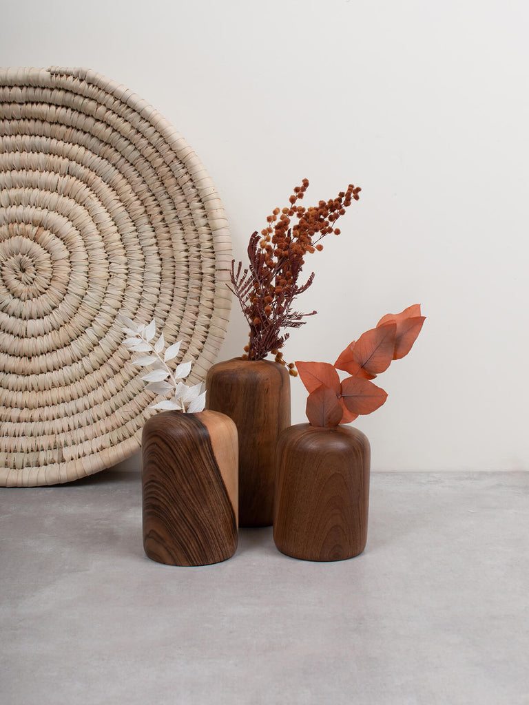 Three walnut wood mini vases by Bohemia Design with dried flower stems with palm leaf woven plate